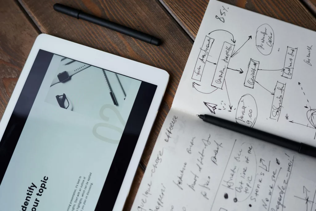 Cette photo montre les outils indispensables au travail d'une agence de publicité à Nantes : une tablette, un carnet et un stylo. Ces outils permettent aux collaborateurs de l'agence de brainstormer, de planifier leurs campagnes et de suivre leurs projets.